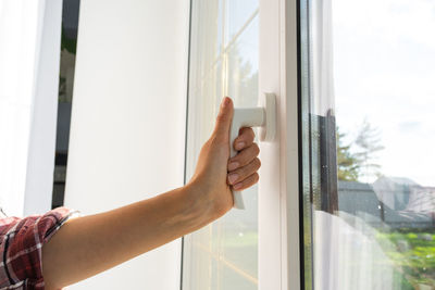 Cropped hand of man holding window