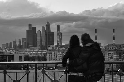 Man and woman looking at city buildings against sky