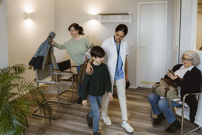 Female doctor taking boy to medical examination room at hospital