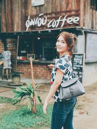 Full length of smiling young woman standing against text