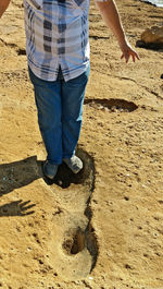 Low section of man standing on sand