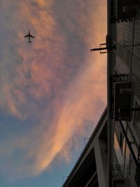 Low angle view of airplane flying against cloudy sky