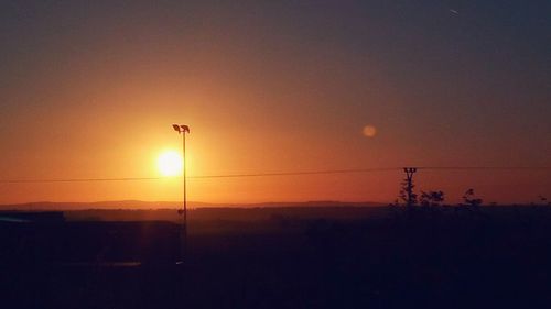 Silhouette electricity pylon against sky during sunset