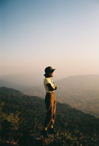 Side view of man standing on mountain against clear sky