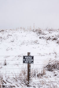 Information sign on snow covered field against sky