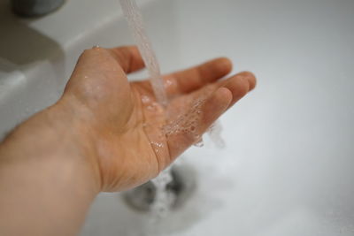 Cropped image of person hand in bathroom