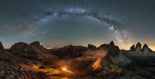 Scenic view of illuminated mountains against sky at dusk