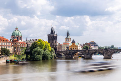 Bridge over river by buildings against sky in city