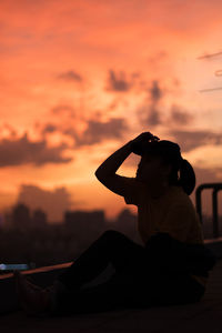 Rear view of woman photographing orange sunset sky