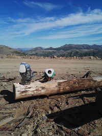 Tripod with machinery on log at mine against blue sky