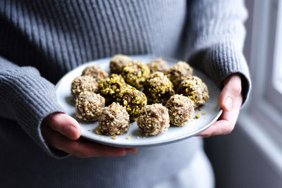 Midsection of woman holding sweet food in plate at home