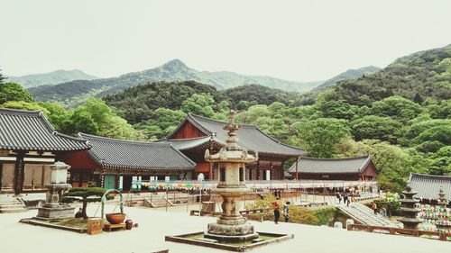 Built structure against trees and mountains against clear sky