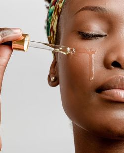 Close-up of young woman applying oil on her face