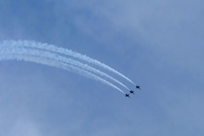 Low angle view of airplanes flying against blue sky