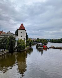 Buildings by river against sky