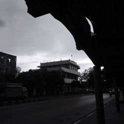 Street by silhouette buildings against sky