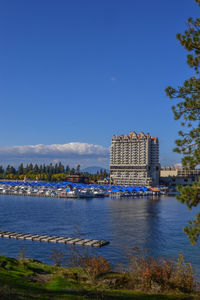 View of buildings by river against blue sky