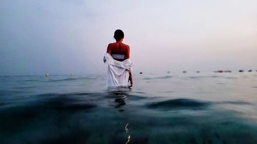 Rear view of man standing at beach against sky