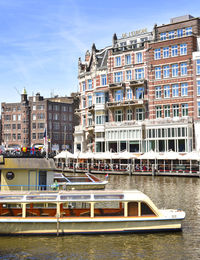 Buildings by river against sky in city