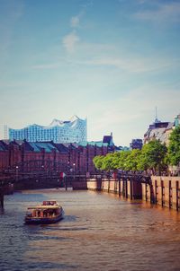 Bridge over river by buildings in city against sky