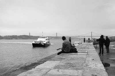 Rear view of woman sitting on pier