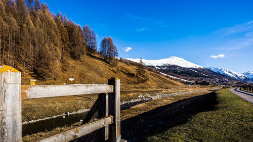 Fence on snowcapped mountain against sky during winter