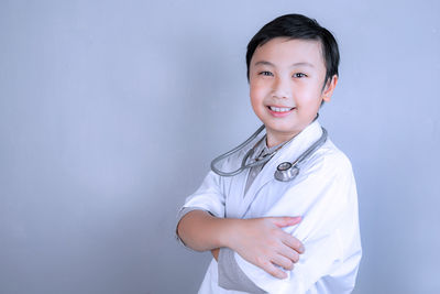 Portrait of smiling boy standing against gray background