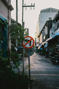 Road sign by street against buildings in city