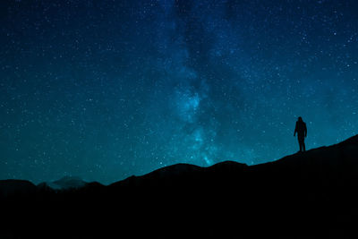 Silhouette woman standing on mountain against sky at night