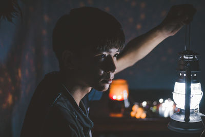 Side view of man holding illuminated lamp