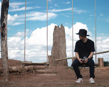 Full length of young man sitting outdoors