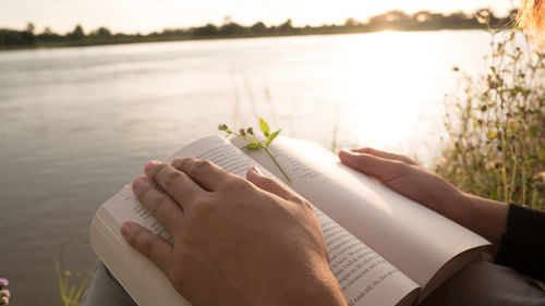 Young woman reading the book at riverside in the evening.