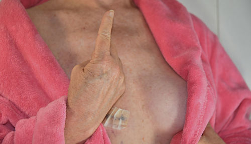 Midsection woman wearing pink bathrobe gesturing with hand