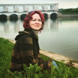 Portrait of smiling young woman against river