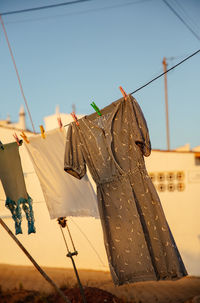 Low angle view of clothes drying on rope against sky