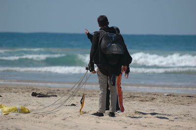 Rear view of man standing with parachute at beach