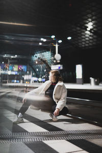 Portrait of young woman standing in city during winter at night