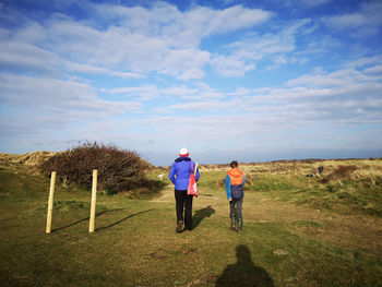 Rear view of man walking with boy on field