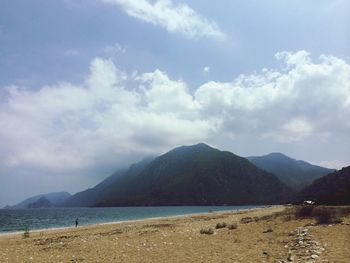View of calm beach against cloudy sky
