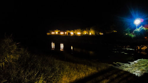 Illuminated field against sky at night