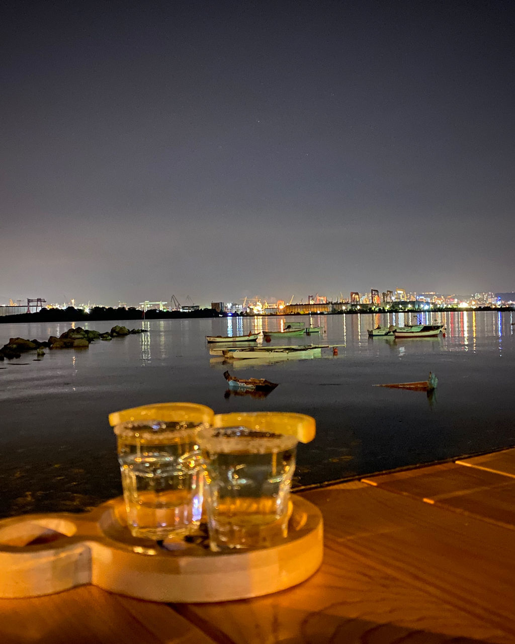 ILLUMINATED COMMERCIAL DOCK AGAINST SKY AT NIGHT