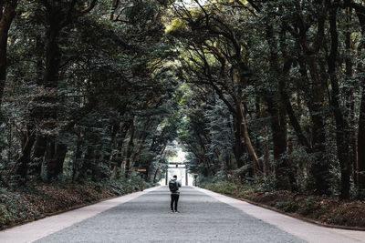 Rear view of woman walking on road in forest