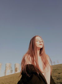 Woman sitting on hill against clear sky