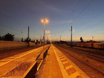 Illuminated railroad station against sky at sunset