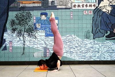 Full length of woman lying on floor against wall