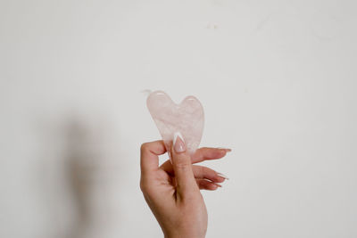 Cropped hand of woman holding flower against blue background