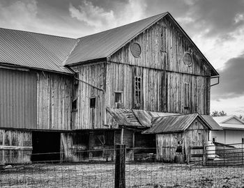 Old barn outside house against sky