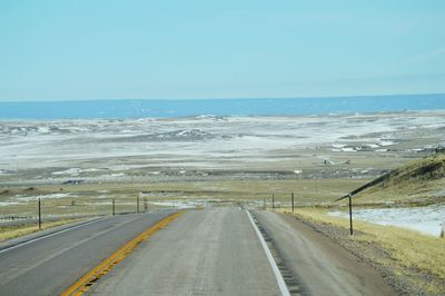 Road toward sea against clear sky