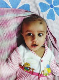 Portrait of cute baby lying on bed