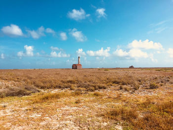 Lighthouse on field against sky